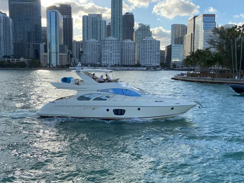 Slide: The Image of 2005 Azimut 55E yacht cruising near city skyline, under a partly cloudy sky. - 1