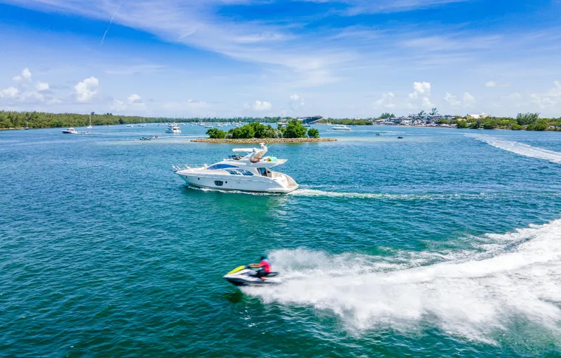 Slide: The Image of 2005 Azimut 55E yacht cruising on a sunny day with a jet ski nearby. - 13