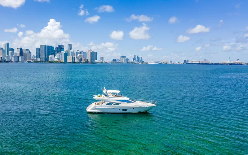 Slide: The Image of Azimut 55E yacht from 2005 on blue water with city skyline in background. - 2