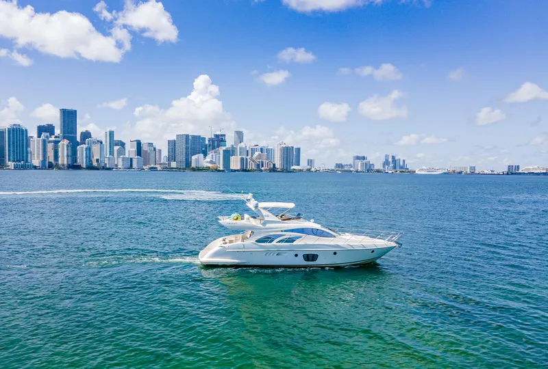 Slide: The Image of 2005 Azimut 55E yacht cruising near a city skyline under a clear blue sky. - 4