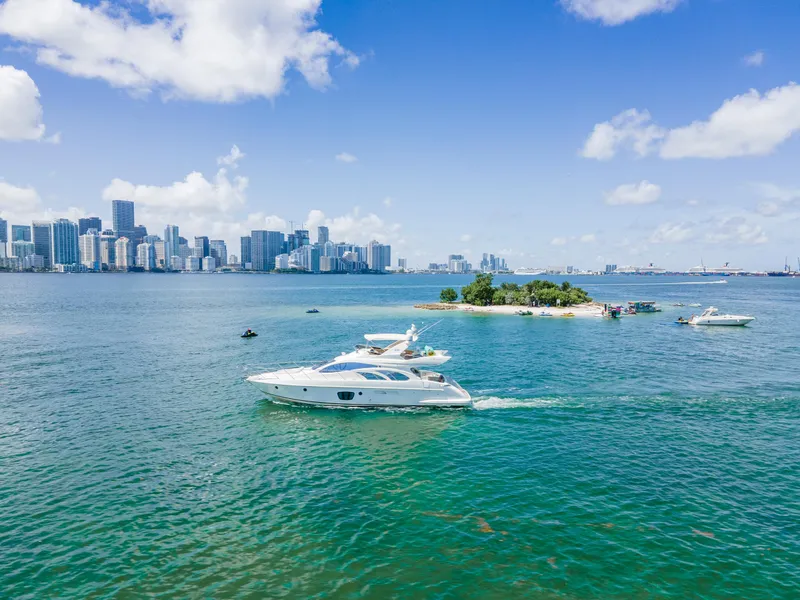 Slide: The Image of Azimut 55E yacht cruising near a small island with city skyline in the background. - 6