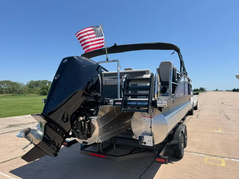 Slide: The Image of 2025 Barletta Cabrio 22UC pontoon boat with American flag, parked on trailer. - 10