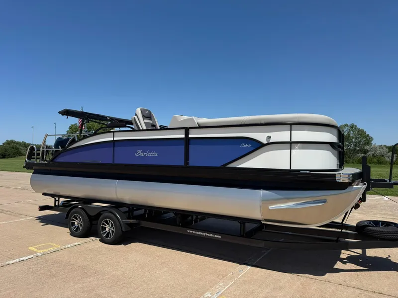 Slide: The Image of 2025 Barletta Cabrio 22UC pontoon boat on trailer under clear blue sky. - 13