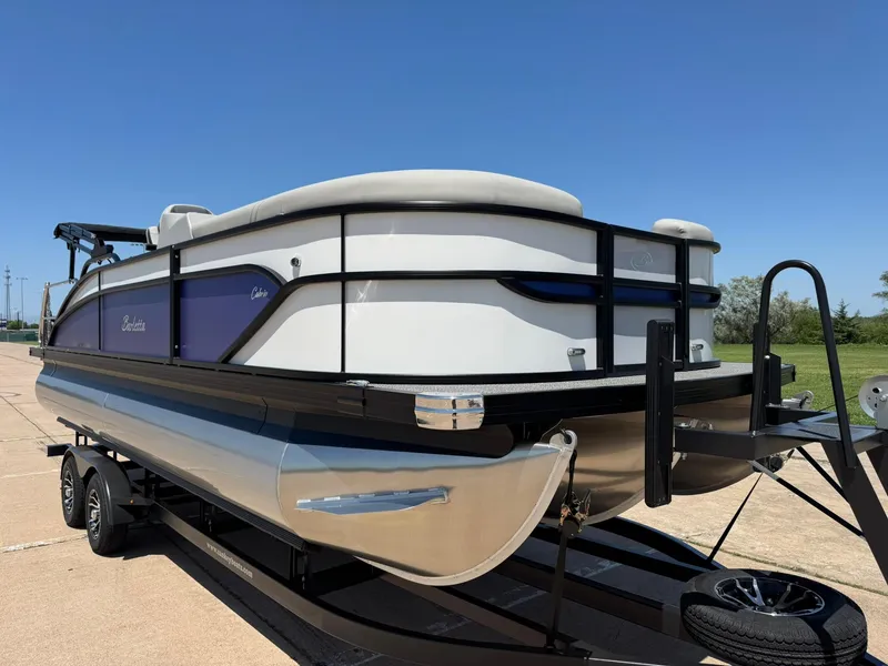 Slide: The Image of 2025 Barletta Cabrio 22UC pontoon boat on trailer, parked outdoors under clear blue sky. - 14