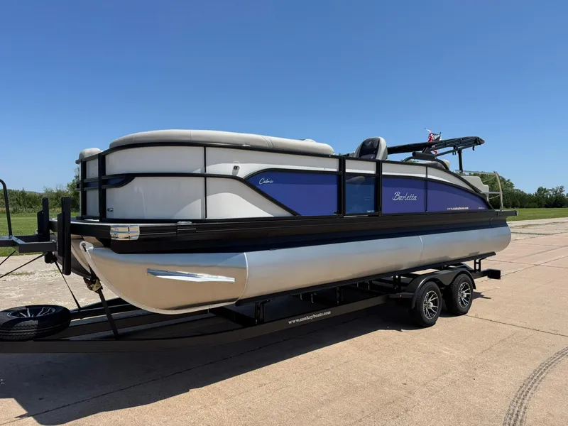 Slide: The Image of 2025 Barletta Cabrio 22UC pontoon boat on trailer, parked outdoors under clear blue sky. - 4