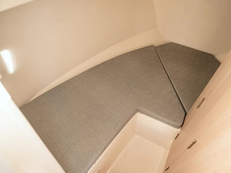 Slide: The Image of 2024 Bayliner Trophy T25PH cabin interior with cushioned seating and storage. - 17