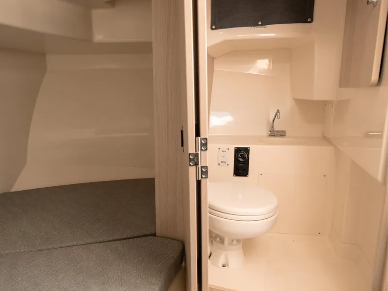 Slide: The Image of 2024 Bayliner Trophy T25PH interior with compact bathroom and cozy sleeping area. - 18