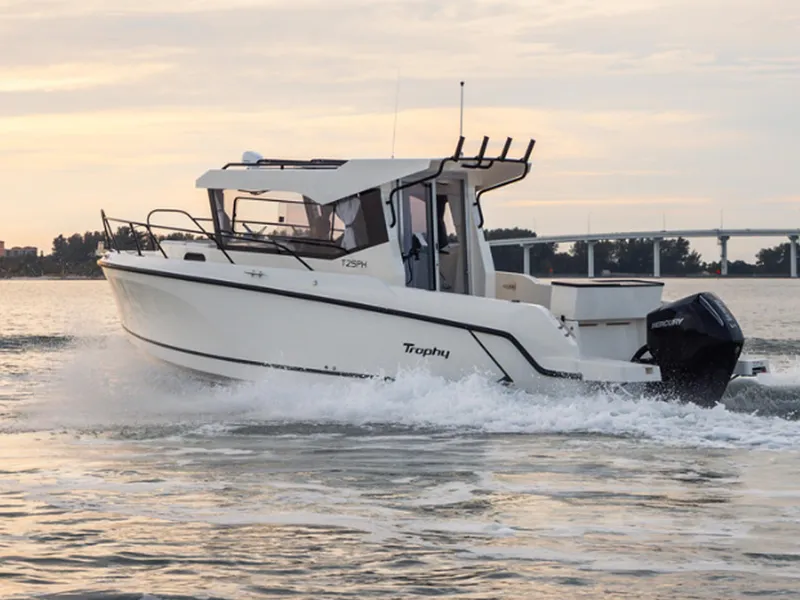 Slide: The Image of 2024 Bayliner Trophy T25PH boat cruising on water at sunset. - 2