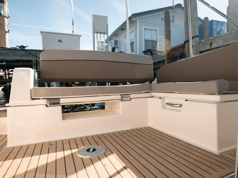 Slide: The Image of 2024 Bayliner Trophy T25PH boat interior with cushioned seating and wooden deck. - 30