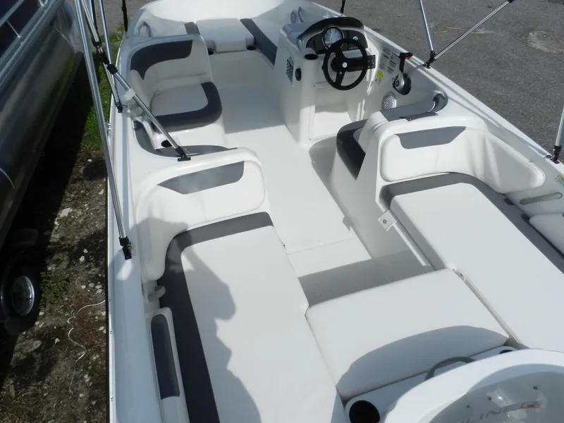 Slide: The Image of 2025 Bayliner E18 boat interior with white and gray seating, steering wheel, and console. - 15