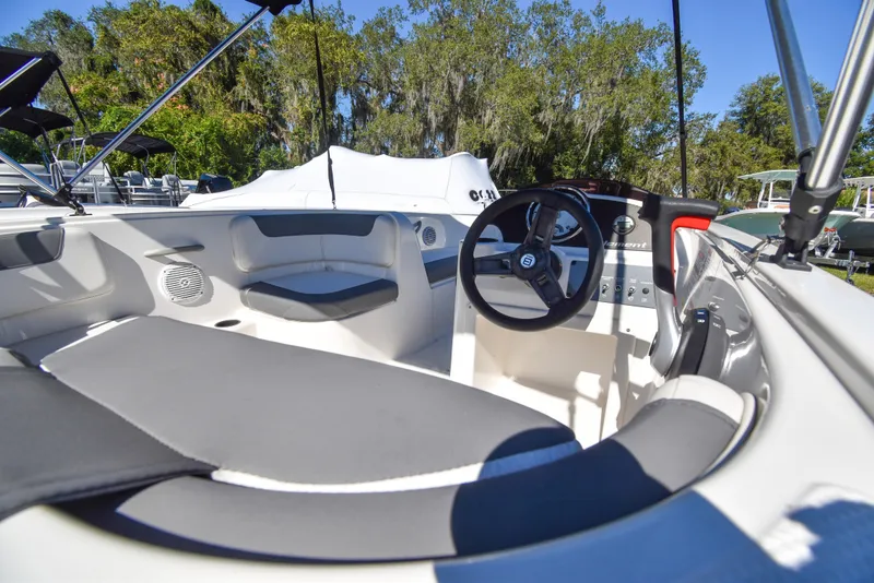 Slide: The Image of 2025 Bayliner E18 boat interior with steering wheel, seating, and console, set against a sunny outdoor backdrop. - 3