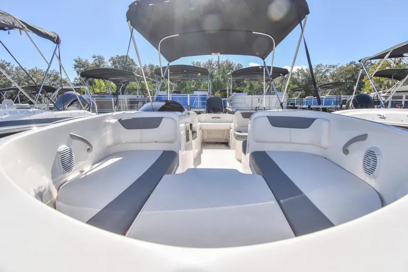Slide: The Image of 2025 Bayliner E18 boat interior with spacious seating and canopy under clear blue sky. - 4