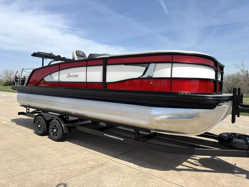 Slide: The Image of 2025 Barletta Lusso 23UC pontoon boat on trailer, red and white design, parked outdoors. - 12