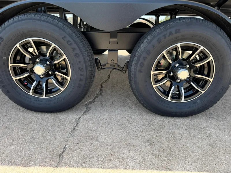 Slide: The Image of 2025 Barletta Lusso 23UC trailer wheels on pavement, featuring Load Star tires and black alloy rims. - 18