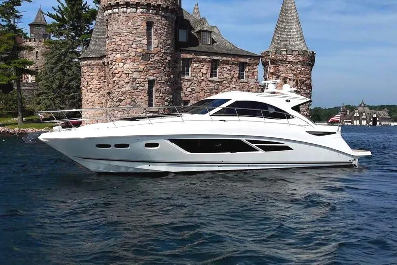 Slide: The Image of 2014 Sea Ray 510 Sundancer yacht cruising near a historic stone castle on a sunny day. - 0