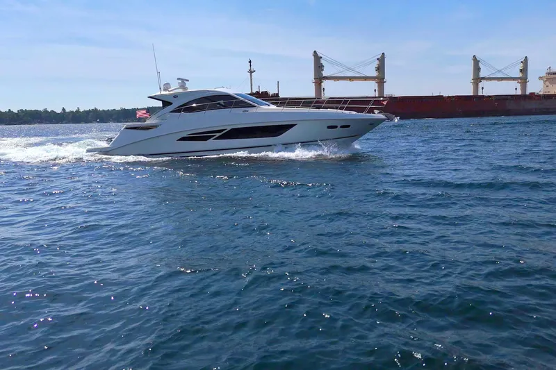 Slide: The Image of 2014 Sea Ray 510 Sundancer cruising on open water with cargo ship in background. - 10