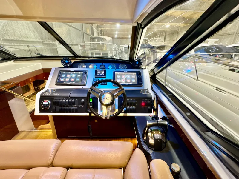 Slide: The Image of 2014 Sea Ray 510 Sundancer helm with modern controls and leather seating in a marina setting. - 28
