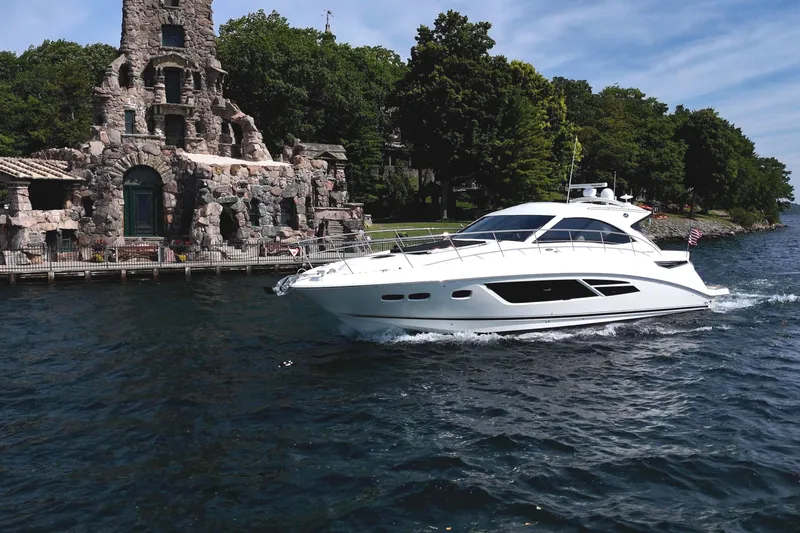 Slide: The Image of 2014 Sea Ray 510 Sundancer yacht cruising near a historic stone building on a sunny day. - 3