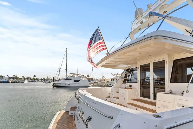 Slide: The Image of 2000 West Bay 58 Sonship yacht docked, displaying American flag, with marina background. - 7
