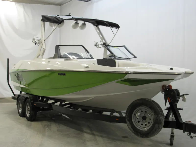 Slide: The Image of 2015 Axis A24 boat with green and white design on a trailer. - 1