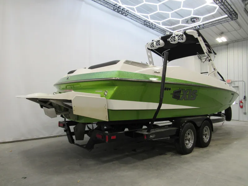 Slide: The Image of 2015 Axis A24 boat in green, parked indoors on a trailer. - 2