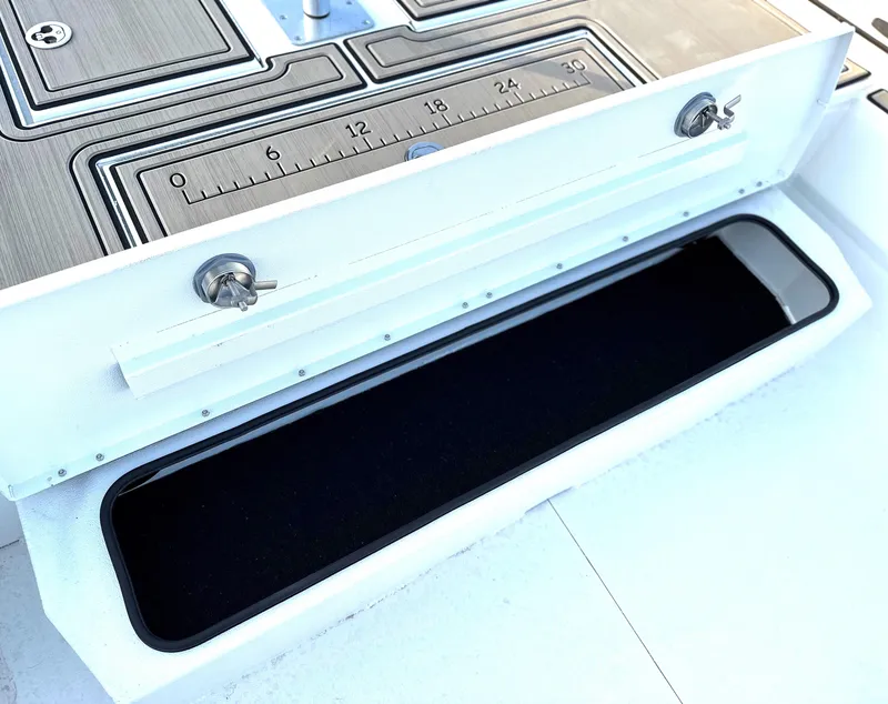 Slide: The Image of Avid Rogue 20 CC 2025 boat storage compartment with ruler and secure latches. - 11