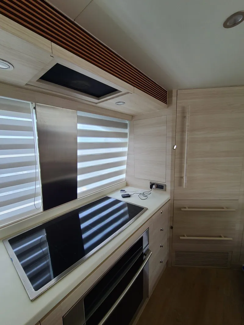 Slide: The Image of Modern kitchen interior in a 2017 Horizon PC60 yacht, featuring sleek appliances and wood finishes. - 13