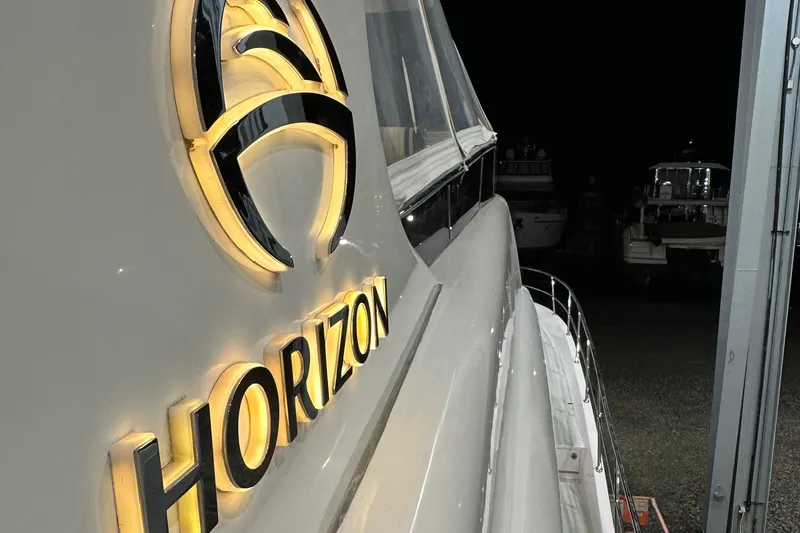 Slide: The Image of Horizon PC60 yacht, 2017 model, illuminated logo at night in a marina setting. - 19