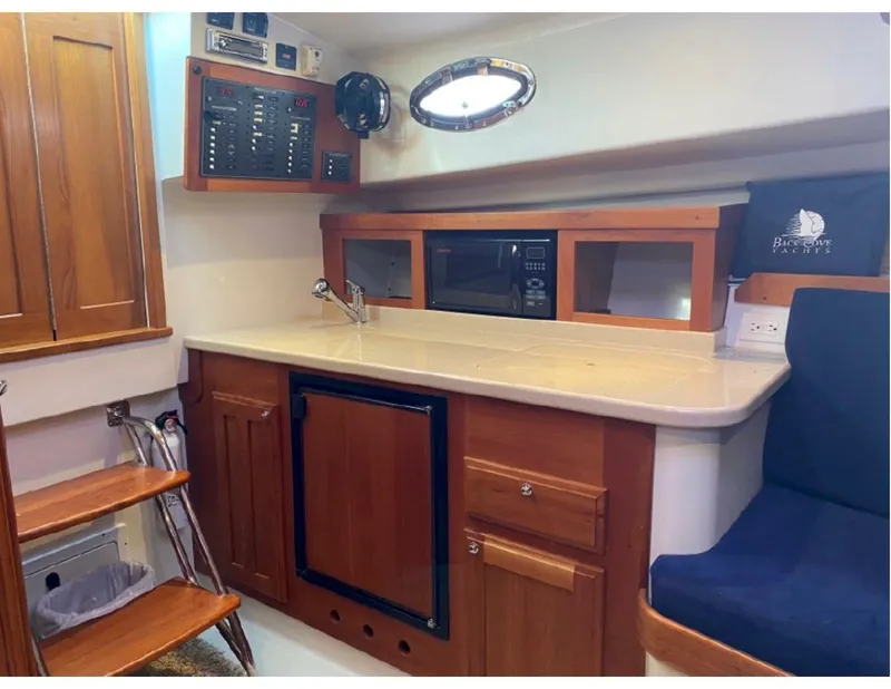 Slide: The Image of 2006 Back Cove 29 yacht interior with kitchenette, featuring wood cabinetry and modern appliances. - 10