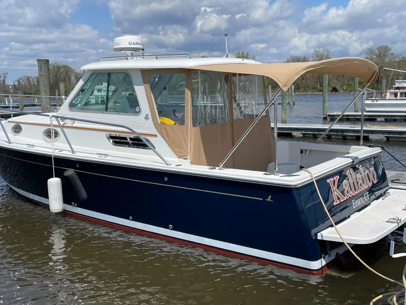 Slide: The Image of 2006 Back Cove 29 boat docked, featuring a navy hull and tan canopy. - 13