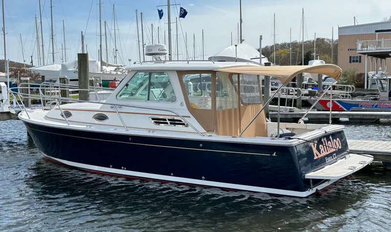 Slide: The Image of 2006 Back Cove 29 boat docked at marina with blue hull and tan canopy. - 15