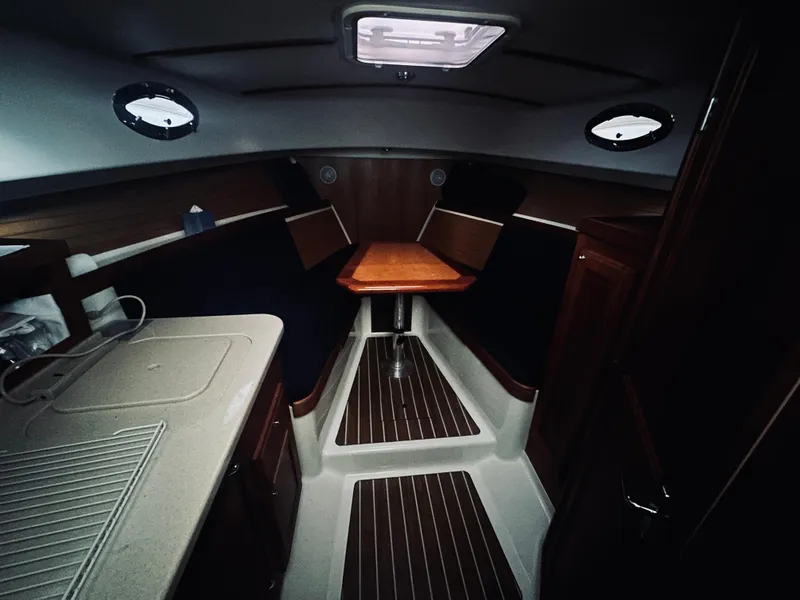 Slide: The Image of 2006 Back Cove 29 interior cabin with wood accents and compact kitchenette. - 9