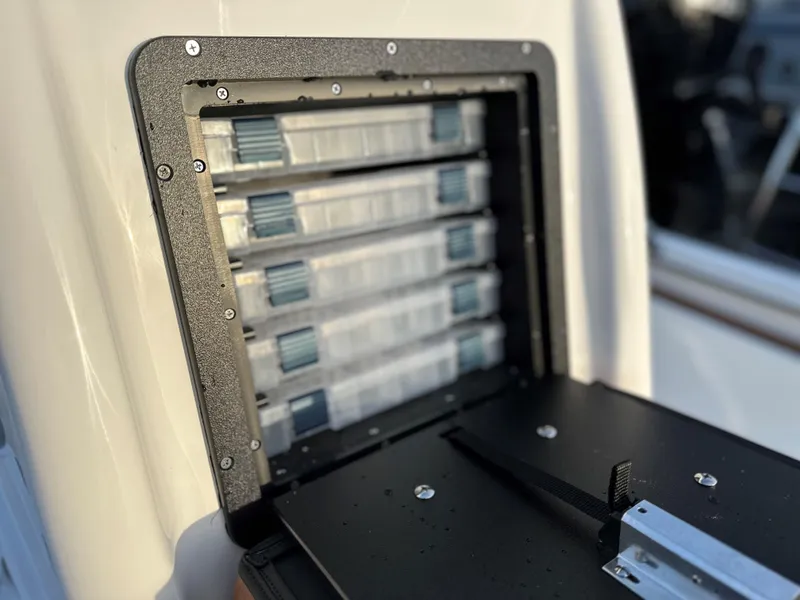 Slide: The Image of Tackle storage compartment on 2025 Avid Rogue 20 CC boat, featuring organized trays. - 6