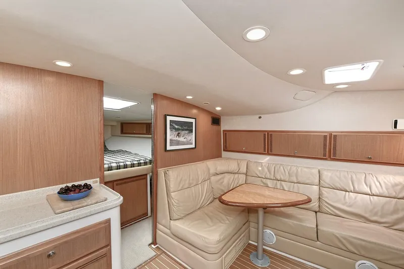 Slide: The Image of 2007 Cabo 40 Express cabin interior with bed, wooden cabinets, and plaid bedding. - 17
