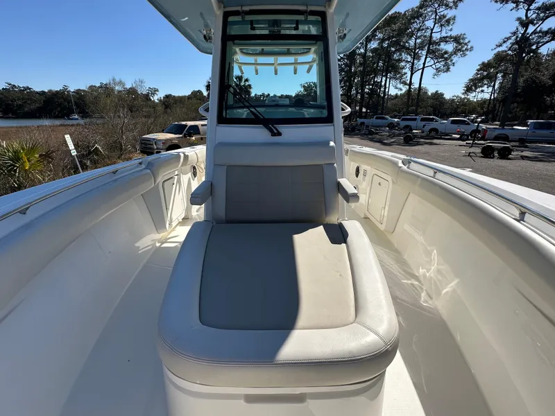 Slide: The Image of 2023 Boston Whaler 280 Outrage boat interior with seating and console, docked outdoors. - 29