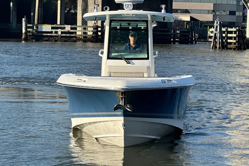 Slide: The Image of 2023 Boston Whaler 280 Outrage boat navigating calm waters near a dock. - 5