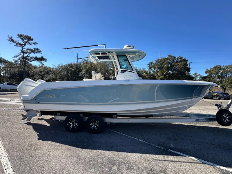 Slide: The Image of 2023 Boston Whaler 280 Outrage boat on trailer, parked outdoors under clear blue sky. - 8