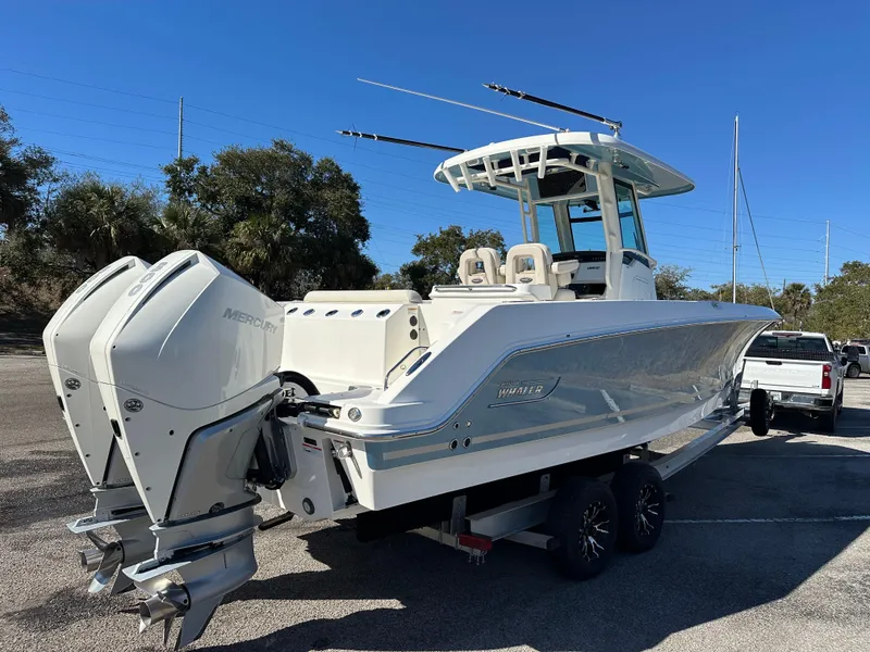 Slide: The Image of 2023 Boston Whaler 280 Outrage boat with dual engines on a trailer, parked outdoors. - 9