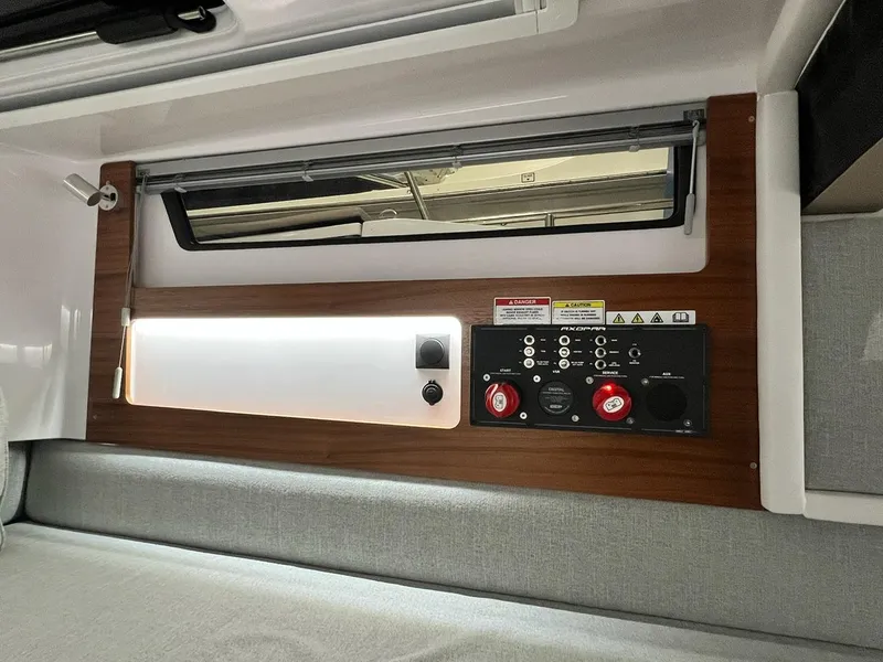 Slide: The Image of 2022 Axopar 28 CABIN interior control panel with wood trim and window. - 19