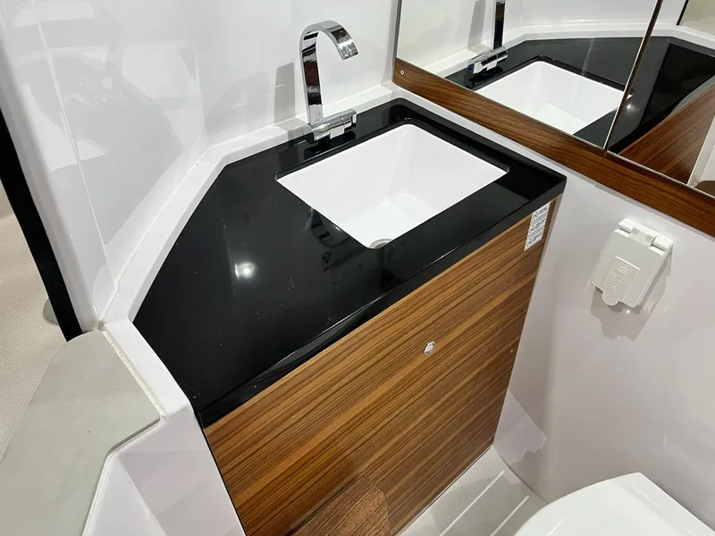 Slide: The Image of 2022 Axopar 28 CABIN bathroom with modern sink and wood accents. - 23