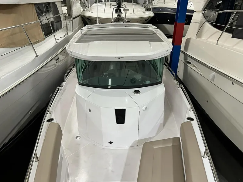 Slide: The Image of 2022 Axopar 28 CABIN boat, white exterior, docked among other vessels. - 9