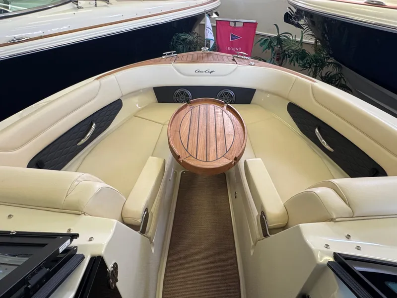 Slide: The Image of 2025 Chris-Craft Sportster 28 boat interior with beige seating and wooden table. - 28