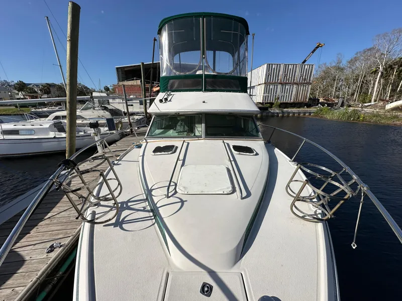Slide: The Image of 1987 Sea Ray 300 Sedan Bridge docked, showcasing spacious deck and flybridge under clear blue sky. - 10