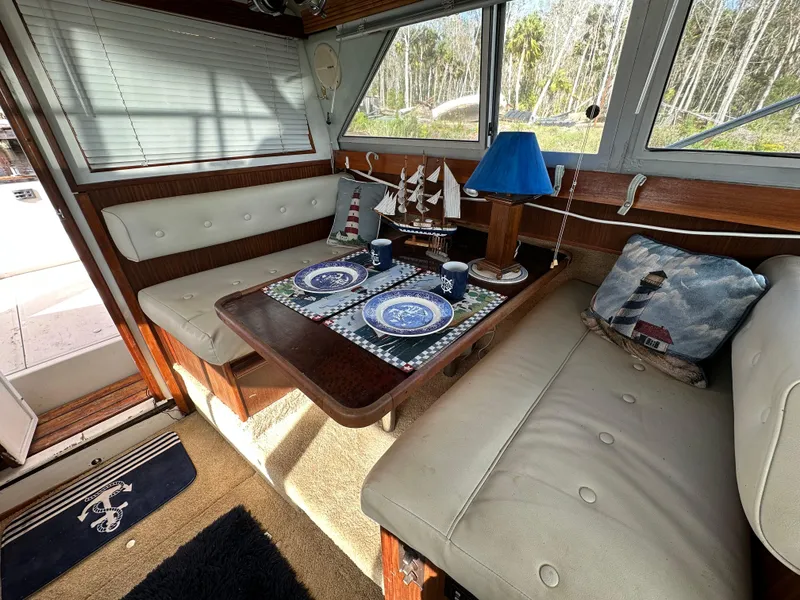 Slide: The Image of 1987 Sea Ray 300 Sedan Bridge interior with nautical-themed dining area and decorative pillows. - 14