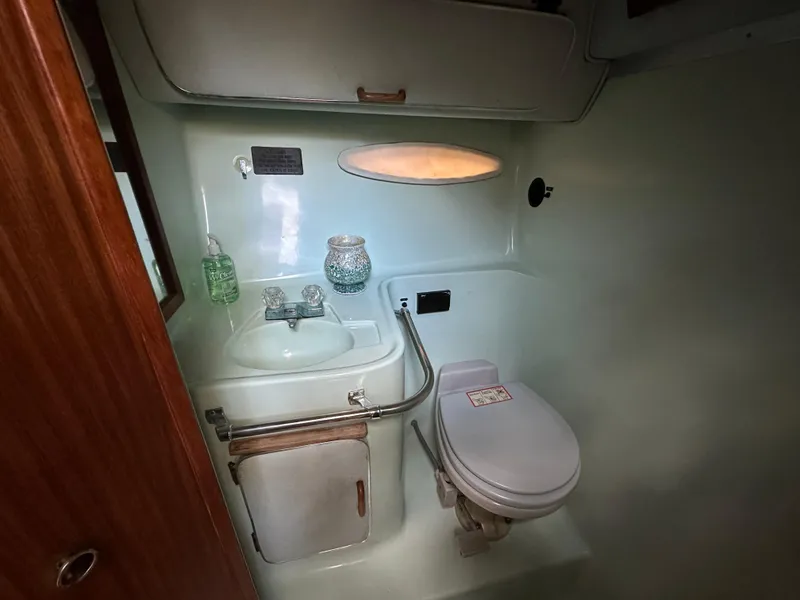 Slide: The Image of 1987 Sea Ray 300 Sedan Bridge bathroom with sink, toilet, and storage cabinet. - 21