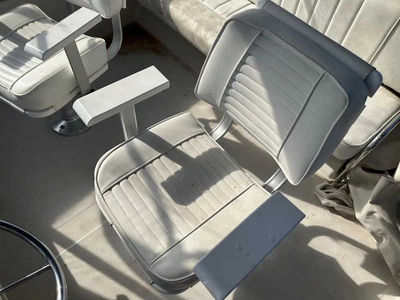 Slide: The Image of Captain's chair on 1987 Sea Ray 300 Sedan Bridge, featuring white cushioned seating and armrests. - 23