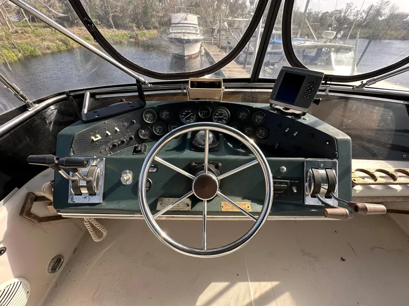 Slide: The Image of 1987 Sea Ray 300 Sedan Bridge helm with steering wheel and navigation controls. - 26