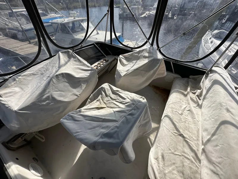 Slide: The Image of 1987 Sea Ray 300 Sedan Bridge interior with covered seats and marina view. - 27