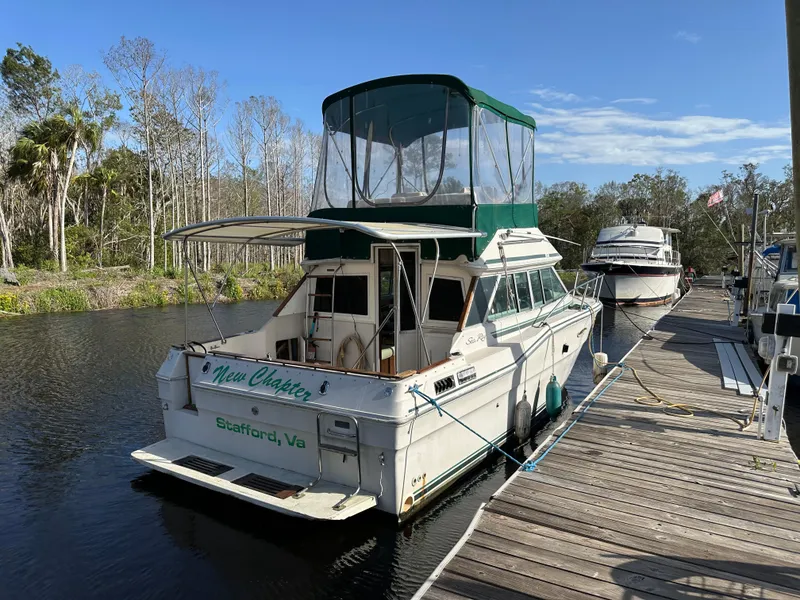 Slide: The Image of 1987 Sea Ray 300 Sedan Bridge docked on a calm river, surrounded by trees. - 5