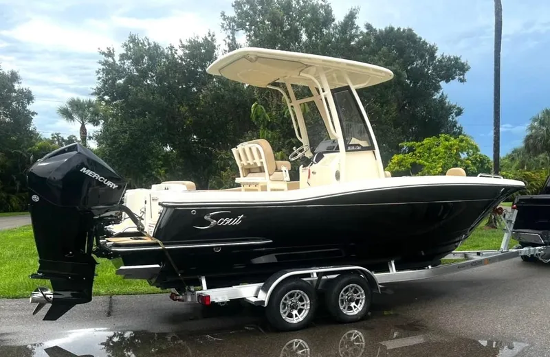 The Image of 2024 Scout 215 XSF boat on trailer with Mercury engine, parked outdoors. - 0